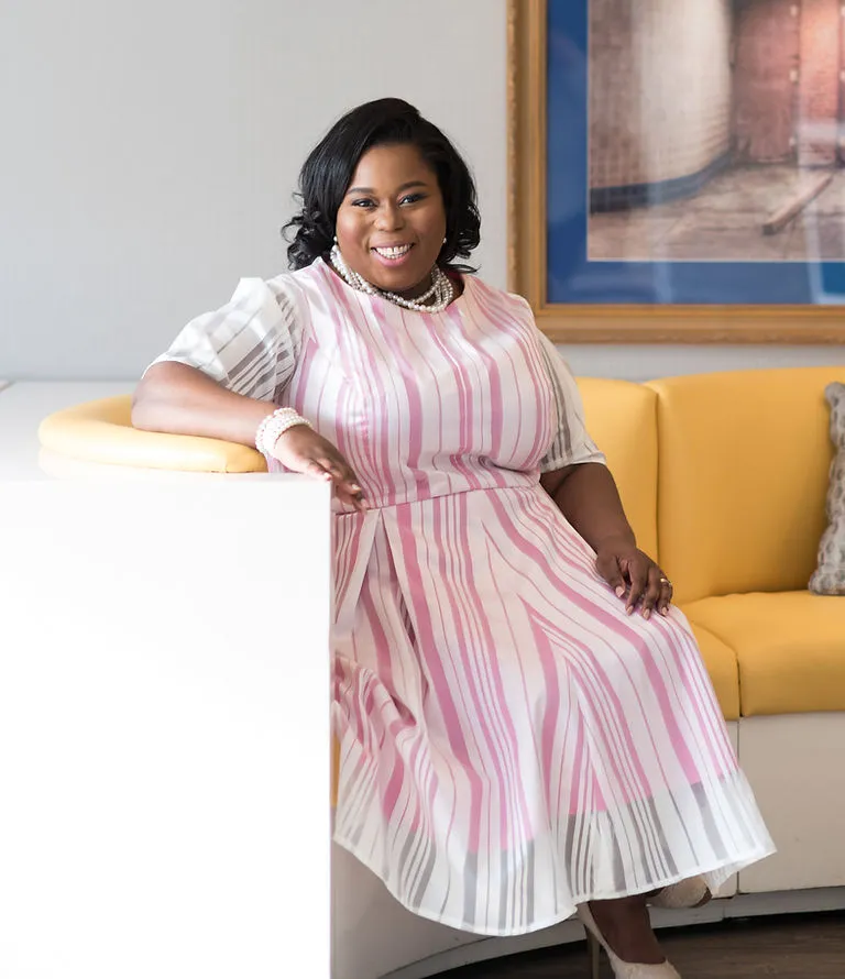 Melissa Jakes seated in a pink and white dress